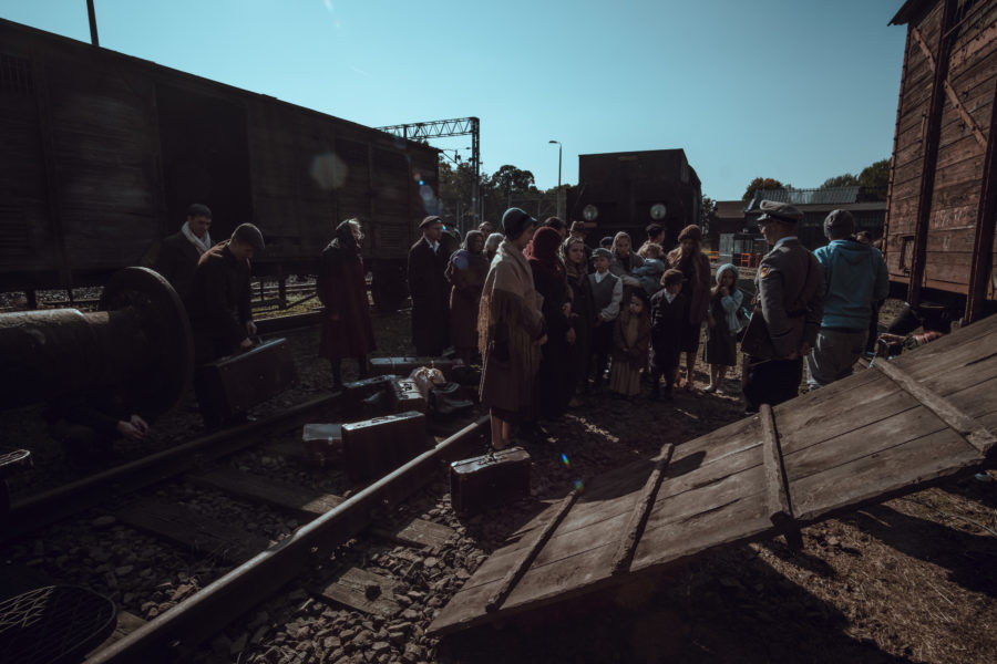 Kadr z filmu „Położna z Auschwitz”. Tłum ludzi czeka przy pociągu towarowym.