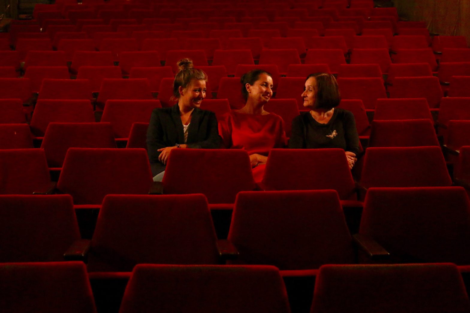 Trzy kobiety rozmawiają w pustej sali kinowej.