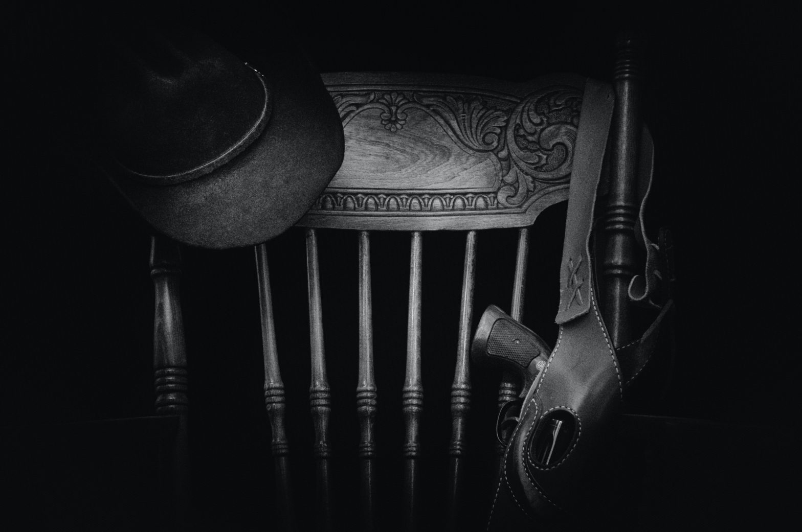 Krzesło, na którym zawieszony jest kapelusz i kabura z rewolwerem.