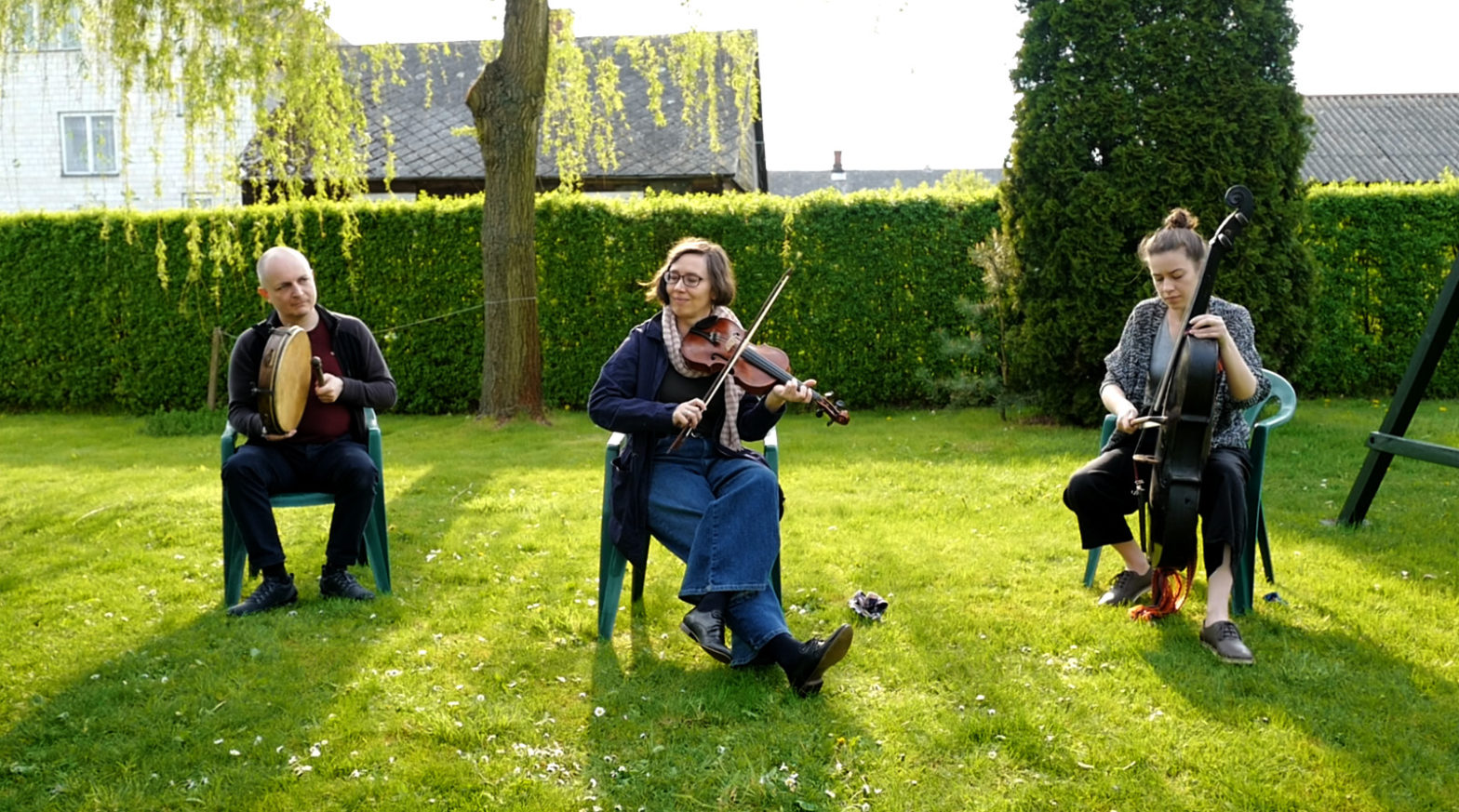 Trzyosobowy zespół odgrywa koncert na trawniku.